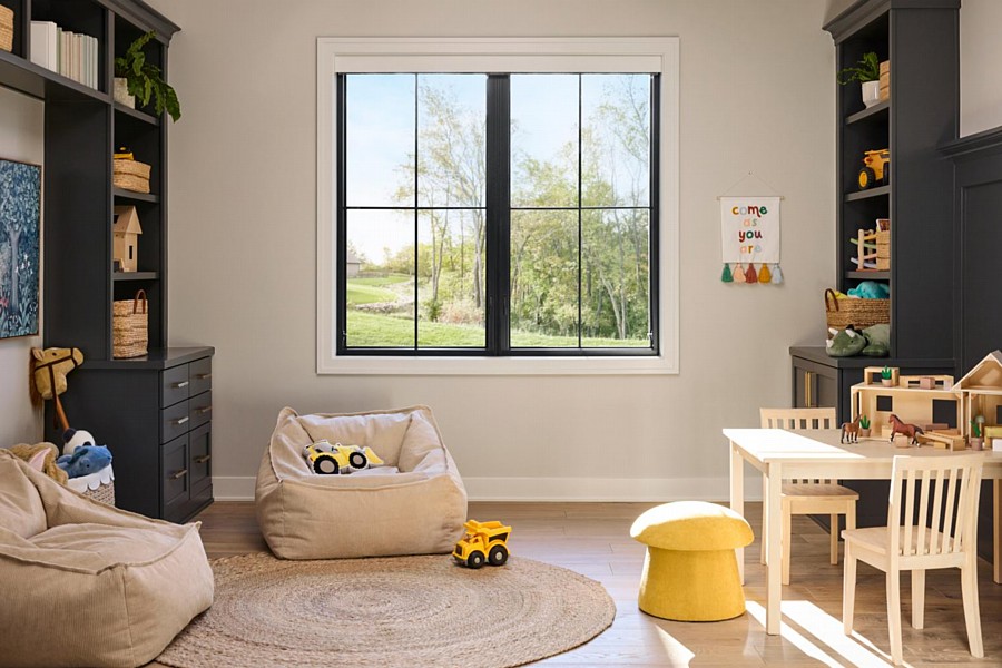 Rustic playroom with tall Pella windows, stone fireplace, and vaulted ceiling