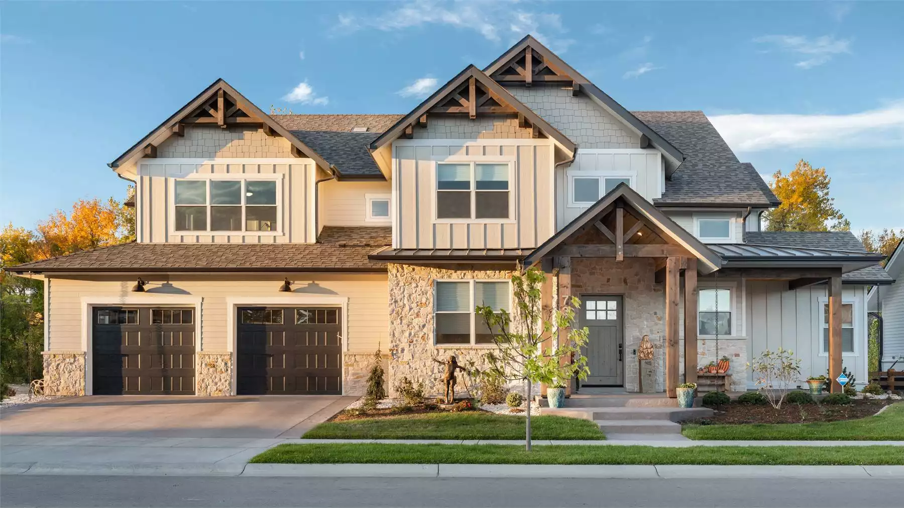 Two-story Modern Farmhouse with board-and-batten siding, stone accents, gabled rooflines, and a covered front porch with timber posts.